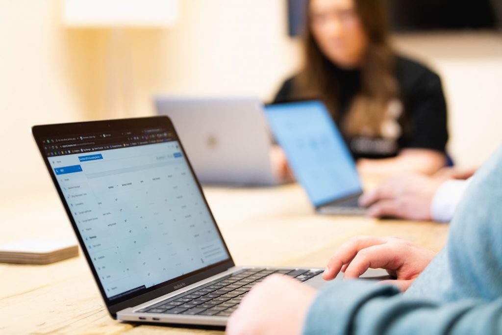 Team members working on laptops around a shared office desk