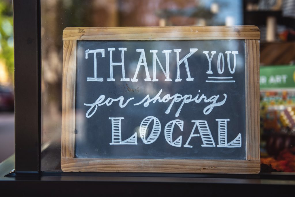 Chalkboard sign in a shop window reading Thank you for shopping local